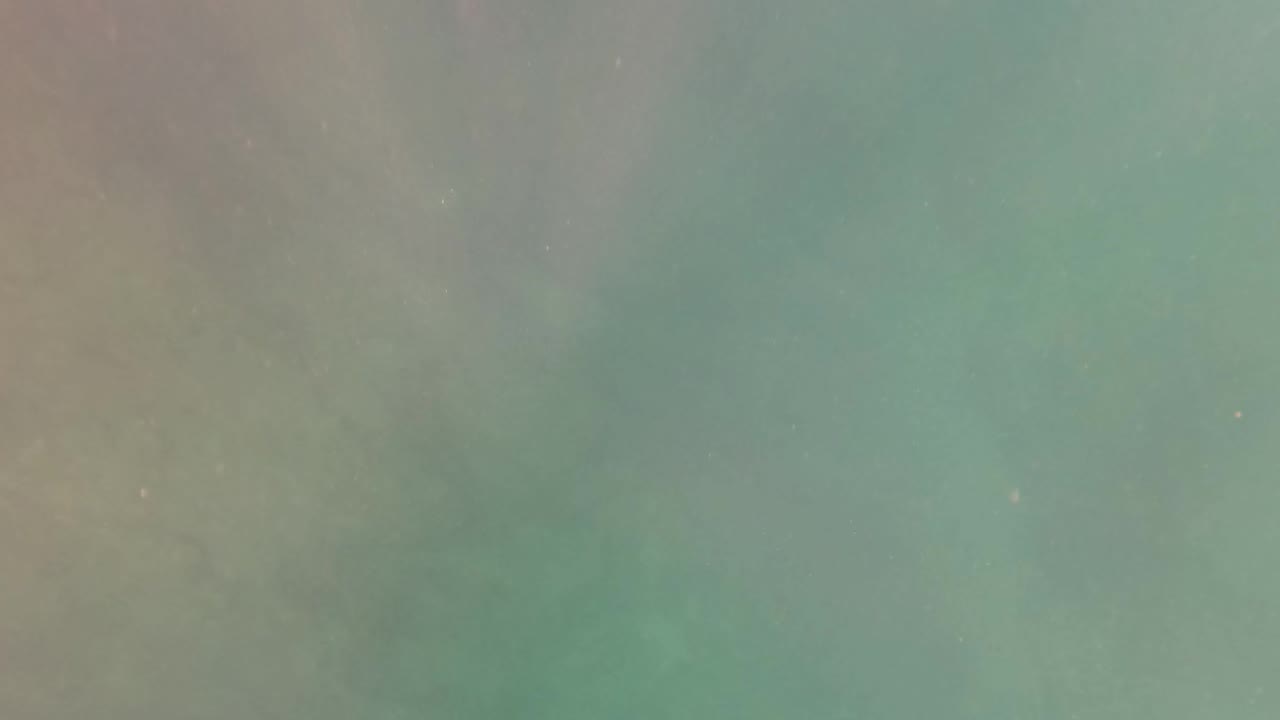 Overhead view of turquoise pool water in San Jose del Cabo with soft cloudy patches, faint ripples, and no visible people at the start of the clip.
