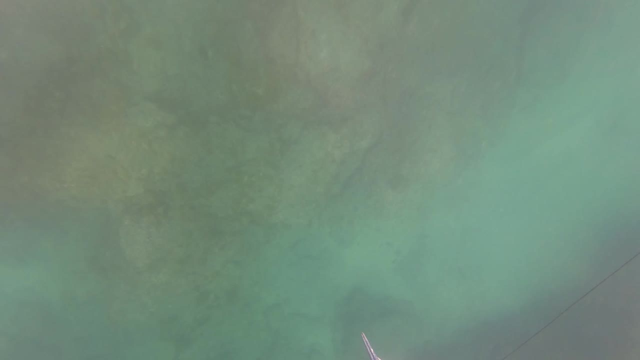 A hazy underwater view in San Jose del Cabo, Baja California Sur shows green-blue water, faint seabed shapes, and a thin diagonal line entering near the lower right, with no recognizable people.