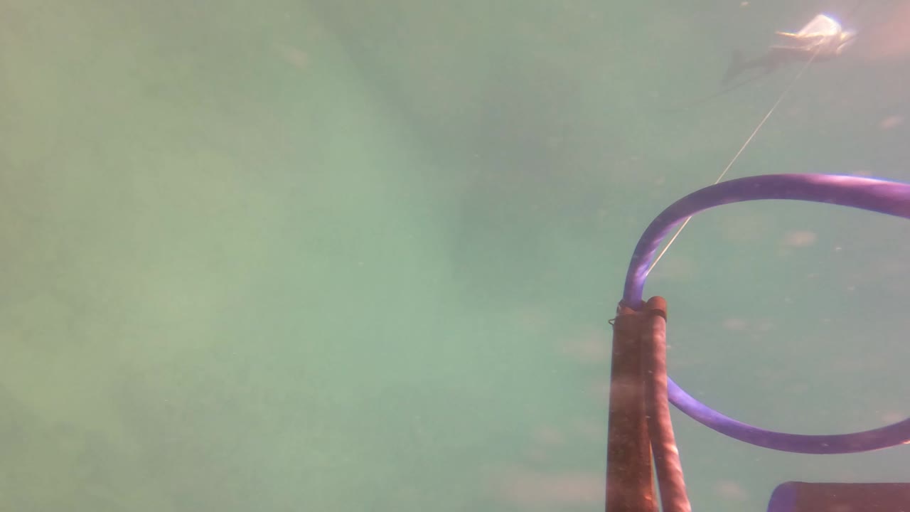The kite control bar is closer to the right edge under green-blue water in San Jose del Cabo, with a thin line stretching upward and no visible people.