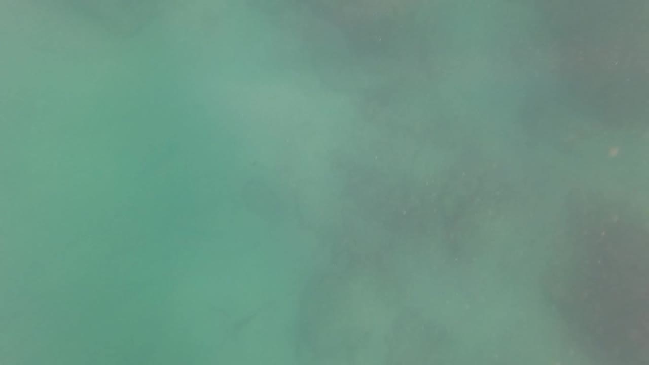 Turquoise underwater view in San Jose Del Cabo with faint seabed rocks below and no visible people.