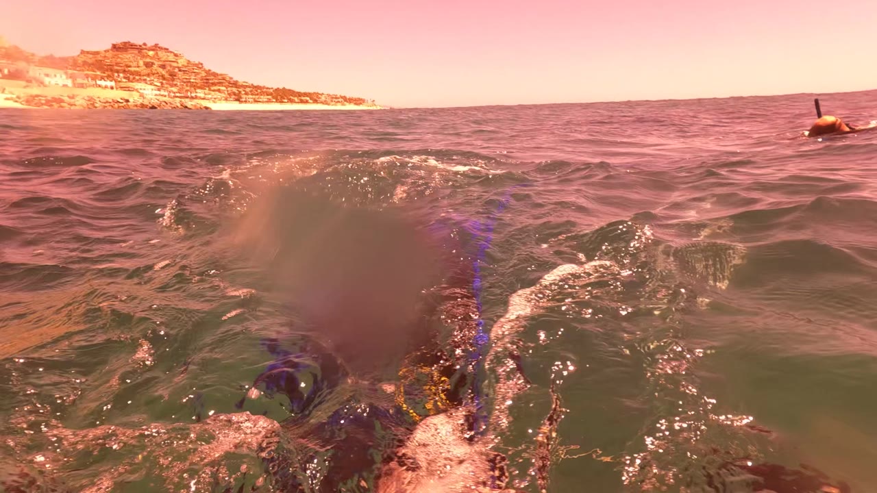 Ocean waves at sunset with coastline in background