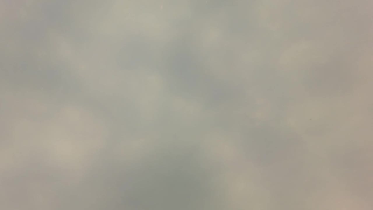 Cloudy underwater frame from San Jose Del Cabo, Baja California Sur, with pale green water, gray-blue haze, blurred bottom detail, and no visible people.