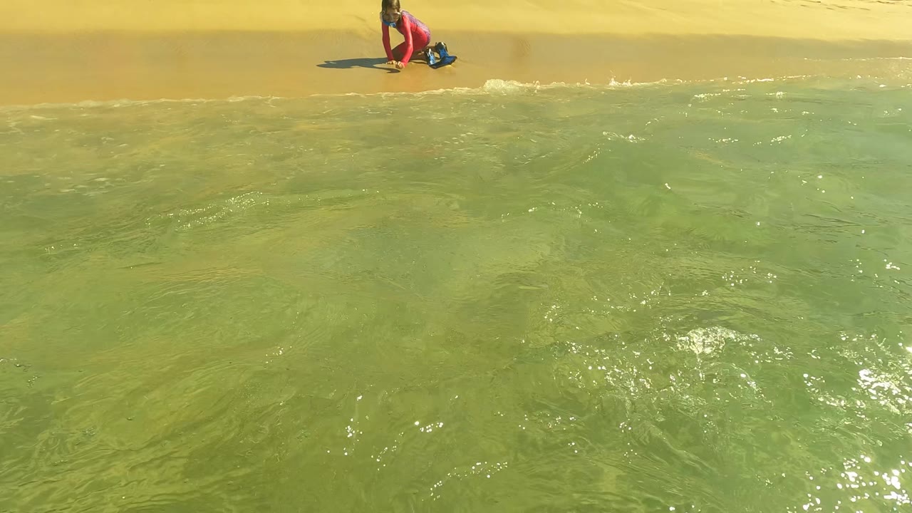 Shallow beach water with child near shoreline in background