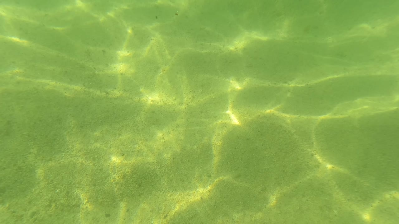 The third frame keeps the sandy seabed full frame, with tighter sunlit ripple shapes across clear green water in San Jose Del Cabo and no visible people.