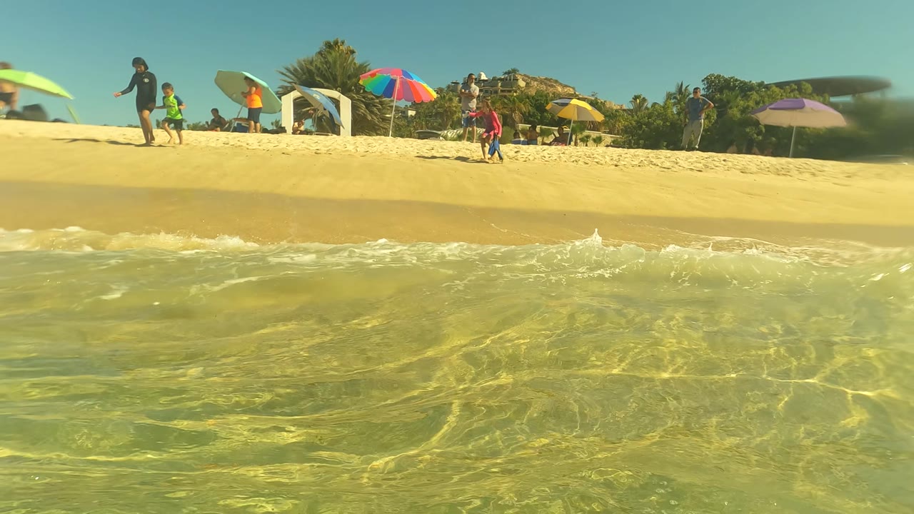 Shoreline water with beach umbrellas and beachgoers in the distance
