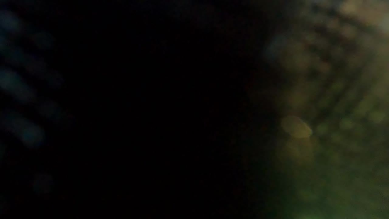 A very dark, blurred section of underwater mesh fills the frame in San Jose Del Cabo, with faint green light and no visible people.