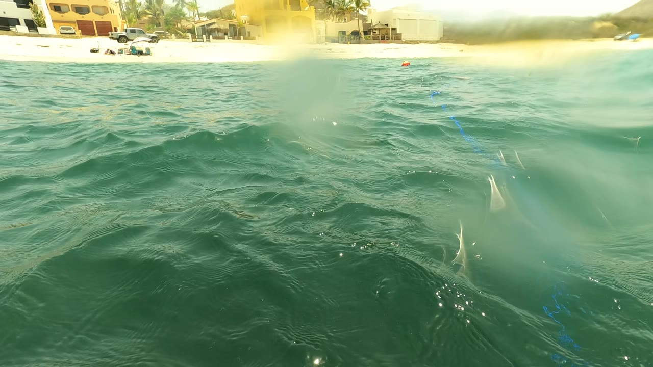 Waterline view of choppy ocean with beach and swimmers in the distance