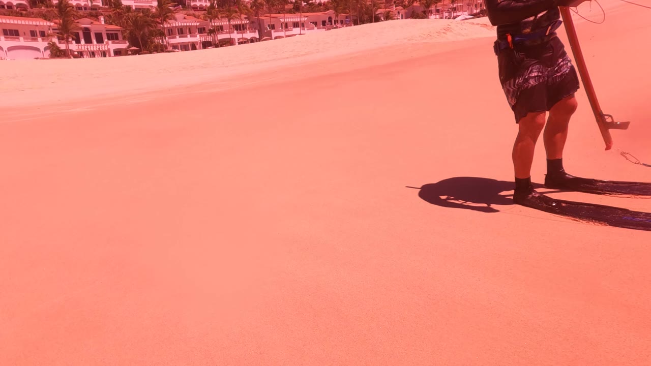 Spearfisher on sand with gear beside the ocean