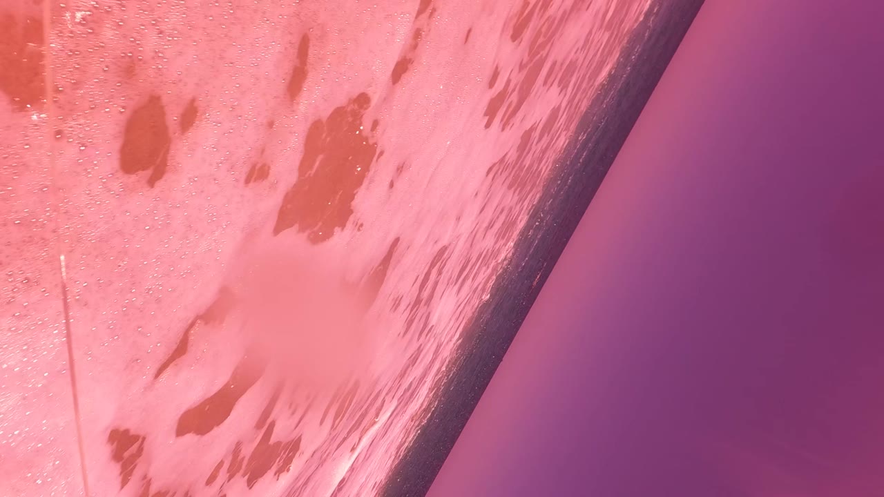 Pink foamy water beside a dark seawall edge