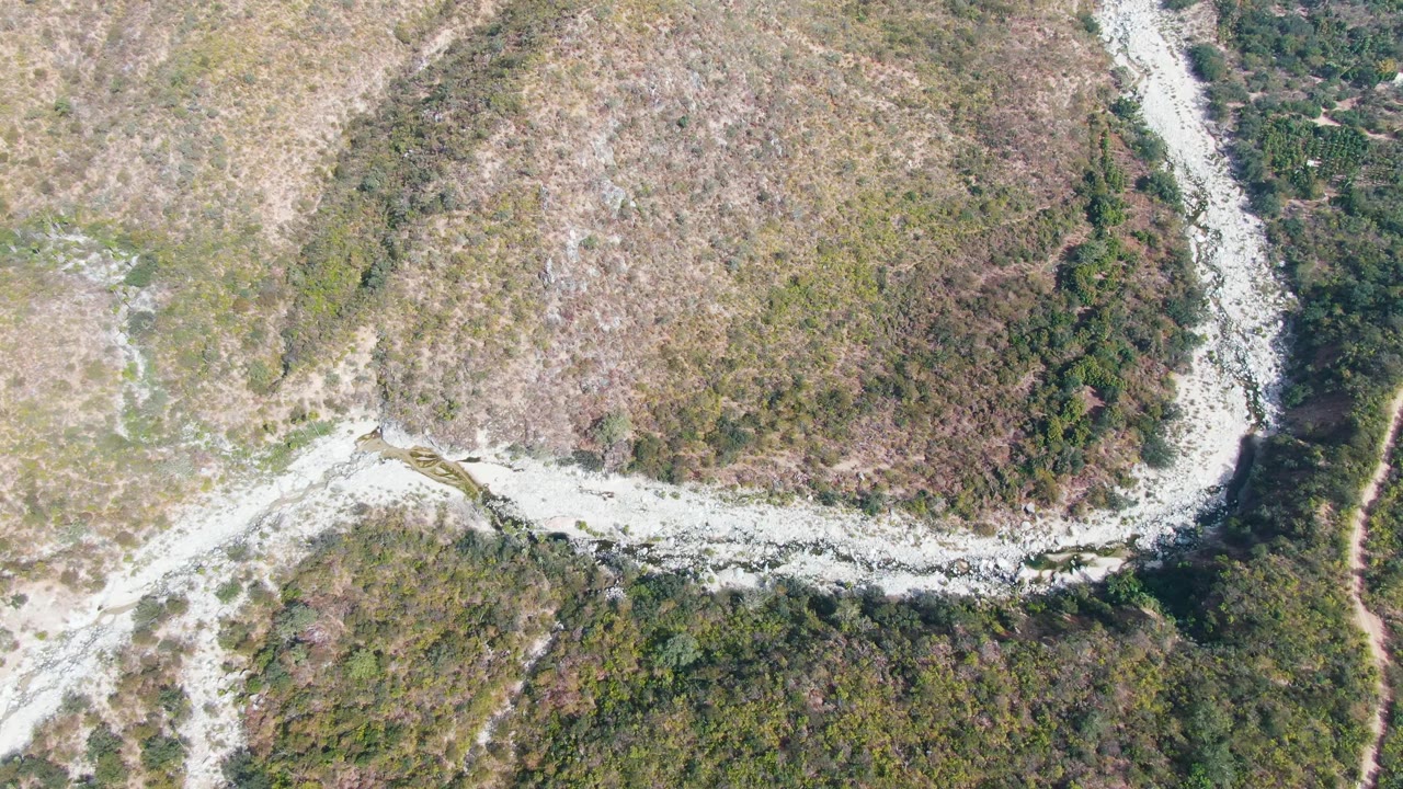 Top-down view from San Dionisio, Baja California Sur showing the pale track beside a darker green vegetation band and brown open ground, with no visible people.