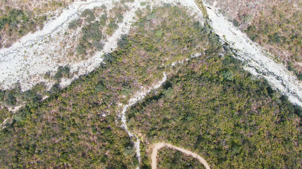 Aerial view of rocky mountain terrain bordered by scrub vegetation.
