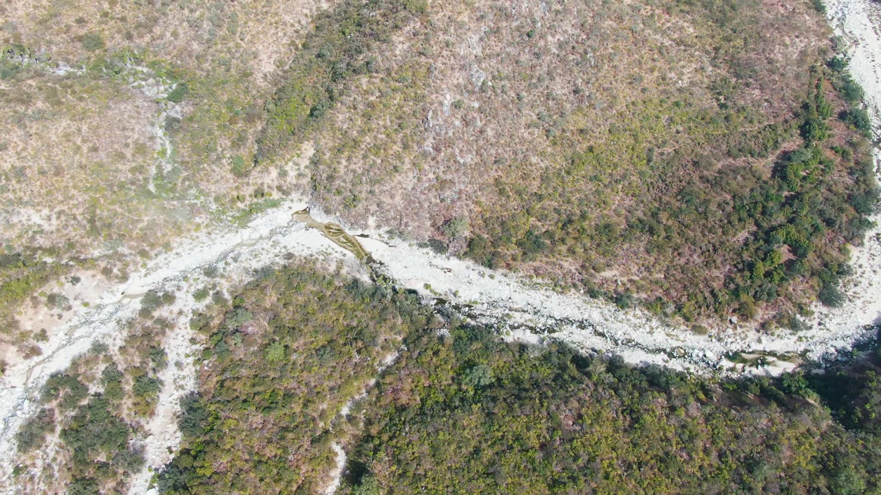 Overhead frame of a pale wash cutting through scrubby brown and green terrain.