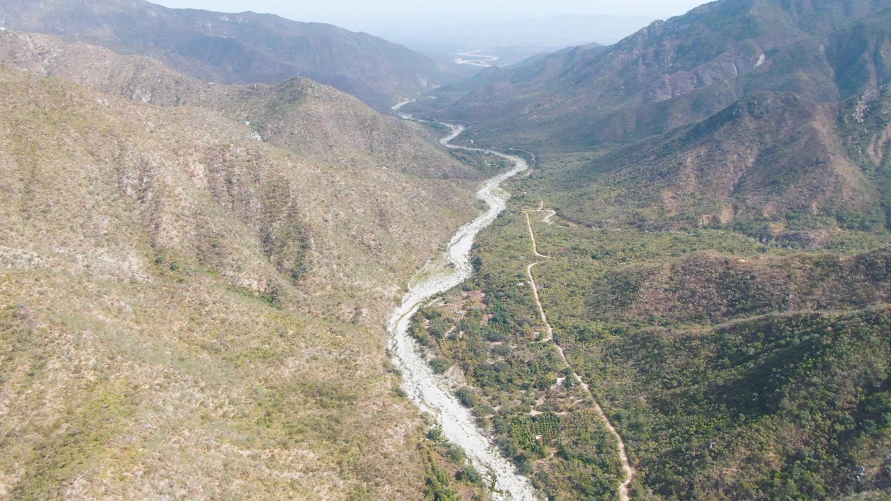 Winding river and road running through dry hills and valley vegetation.