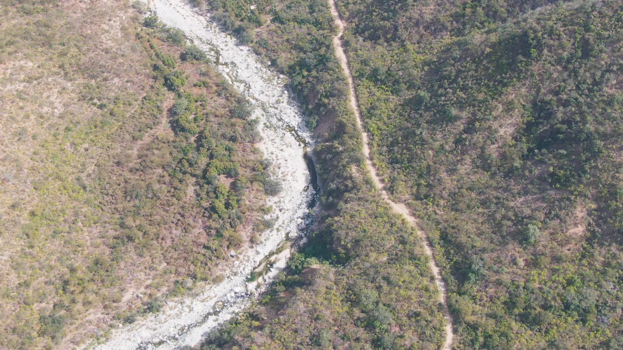 Rocky streambed and dirt path crossing dry hilly vegetation