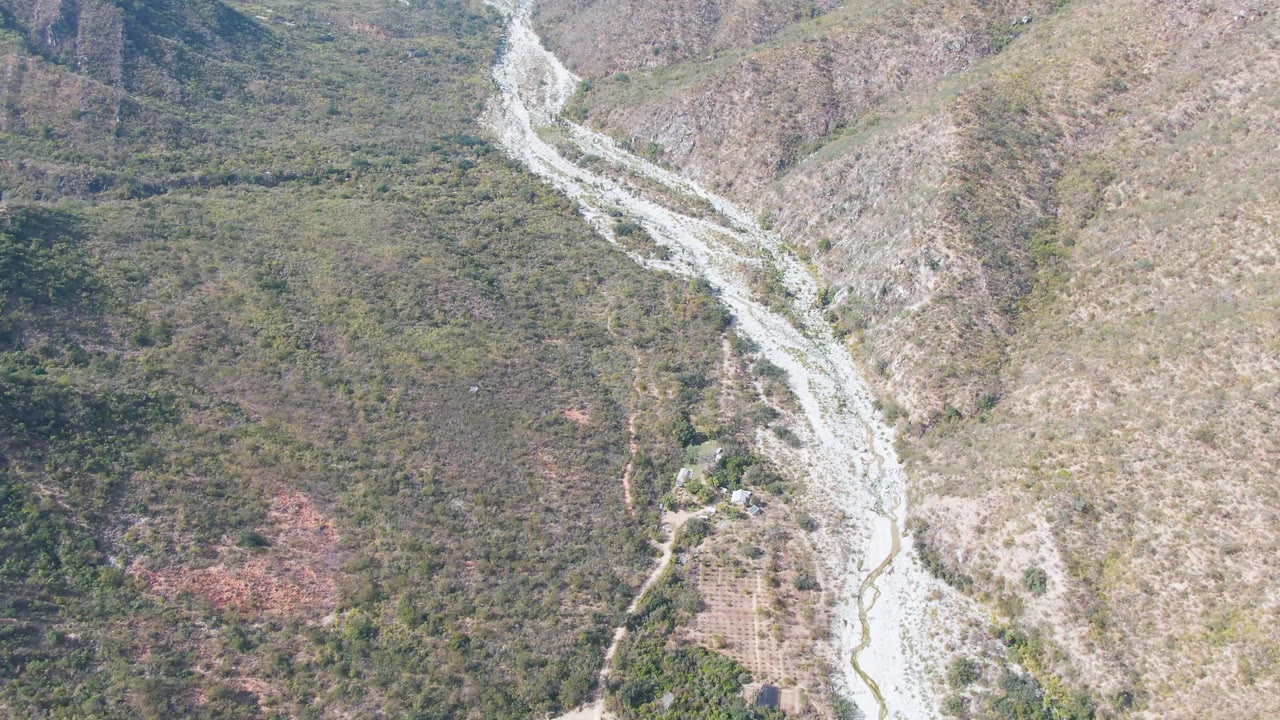 Aerial view in San Dionisio, Baja California Sur, with the riverbed bending diagonally past brushy hillsides and no visible people.