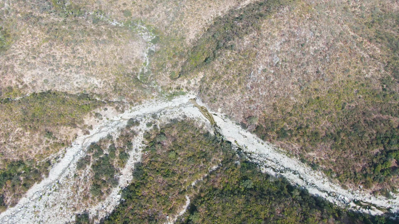Overhead view of a pale winding rocky route through dry scrub hills.