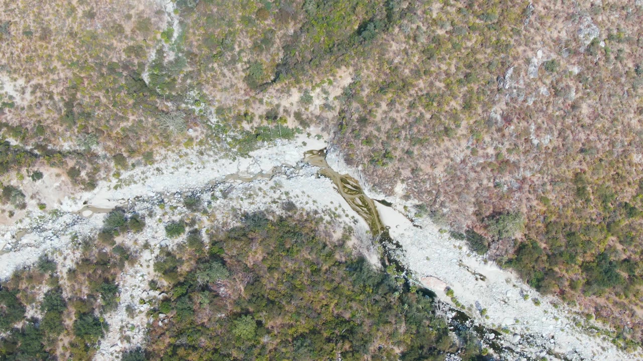 Aerial frame over San Dionisio terrain showing the river bend, light rocky banks, scrub vegetation, and no visible people.