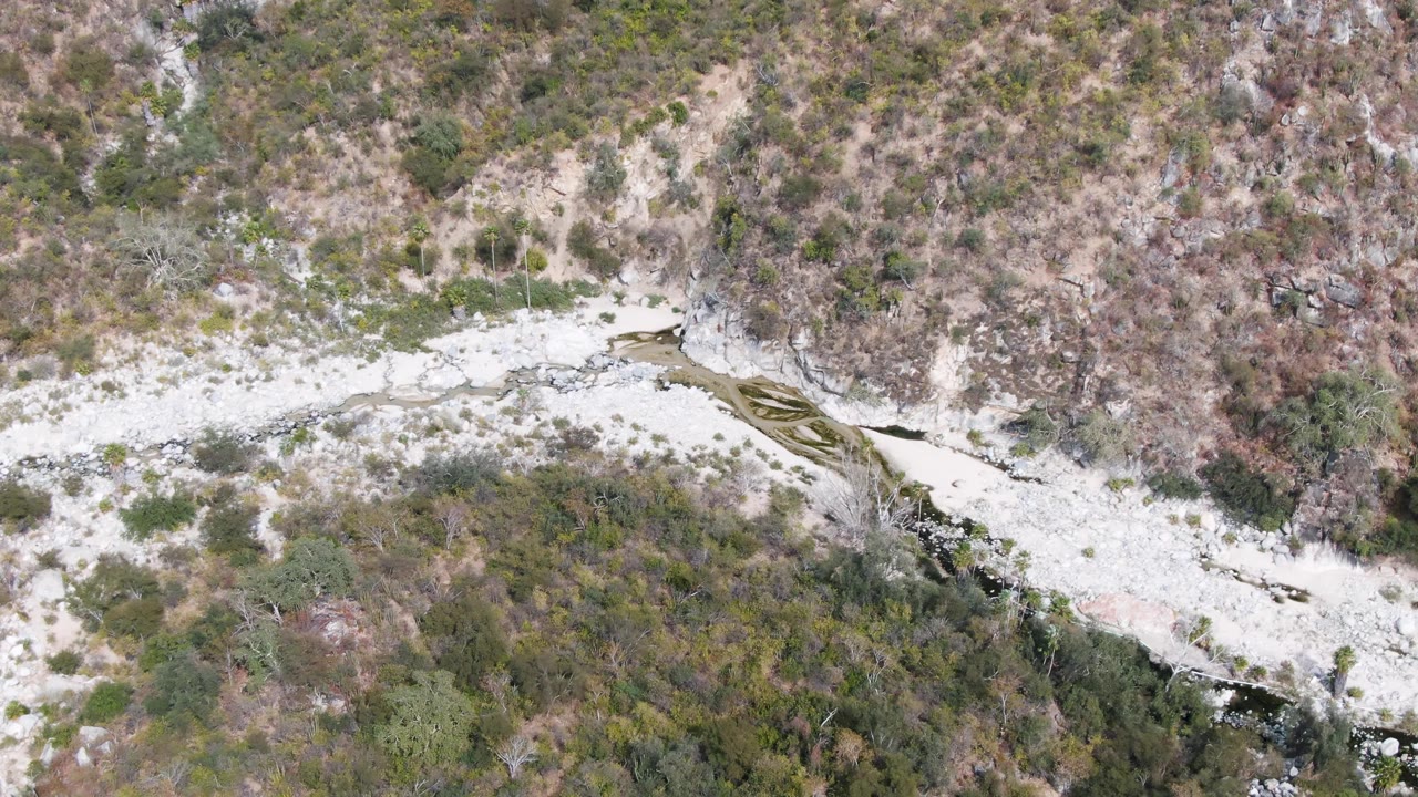 Overhead view of a rocky stream bed crossing scrubby hillsides.