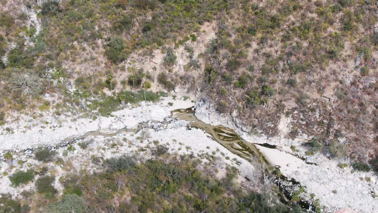 Second frame over San Dionisio, Baja California Sur with the rocky wash centered lower in frame, scrubby hillside above, and no visible people.