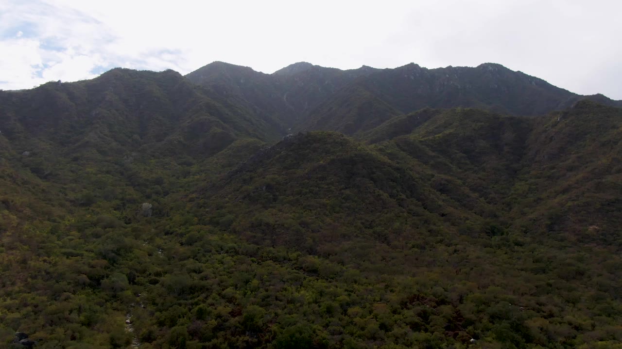 Darker aerial view of the mountain valley beneath an overcast sky.