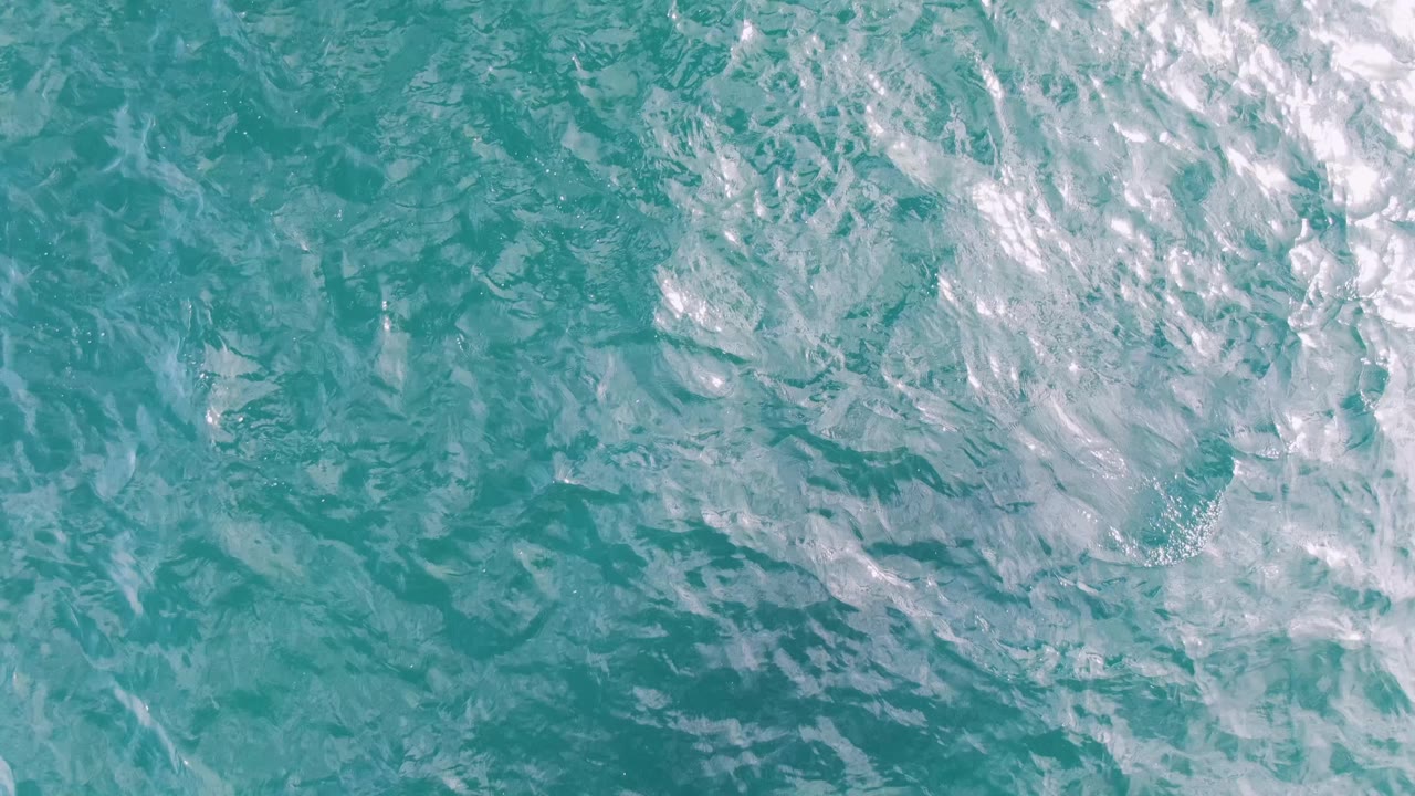 Overhead view of Shipwrecks, Baja California Sur ocean water, with a broad white wake texture crossing turquoise ripples and no visible people.
