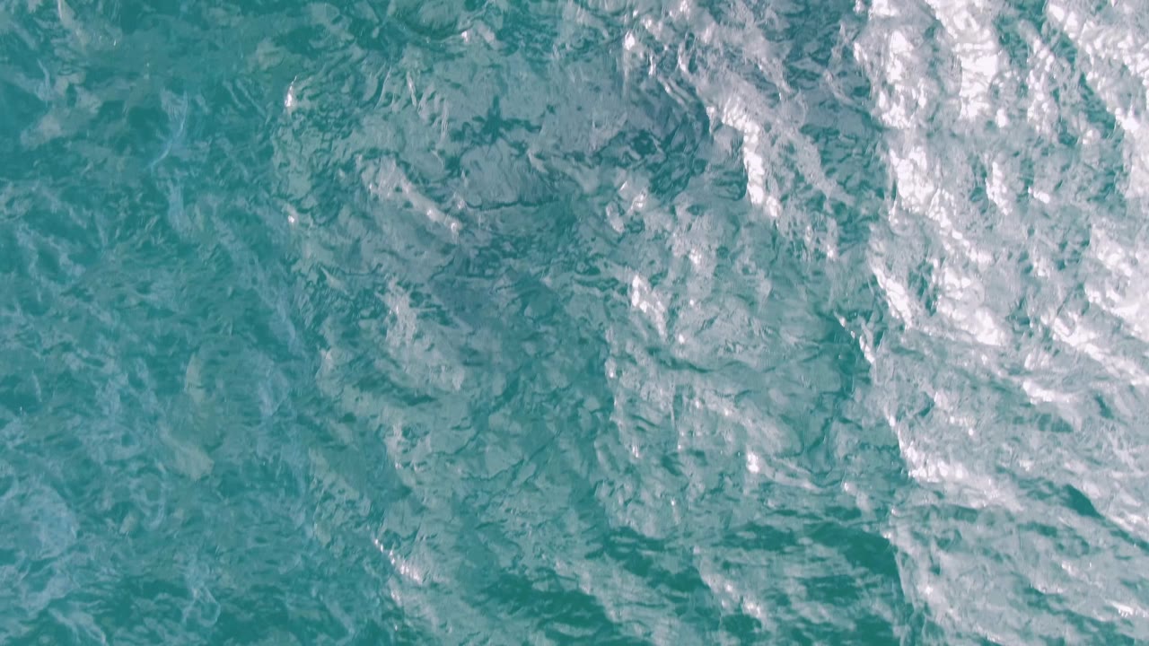 Top-down view of turquoise ocean at Shipwrecks, Baja California Sur, with white foam clustered along the upper right and no visible people.