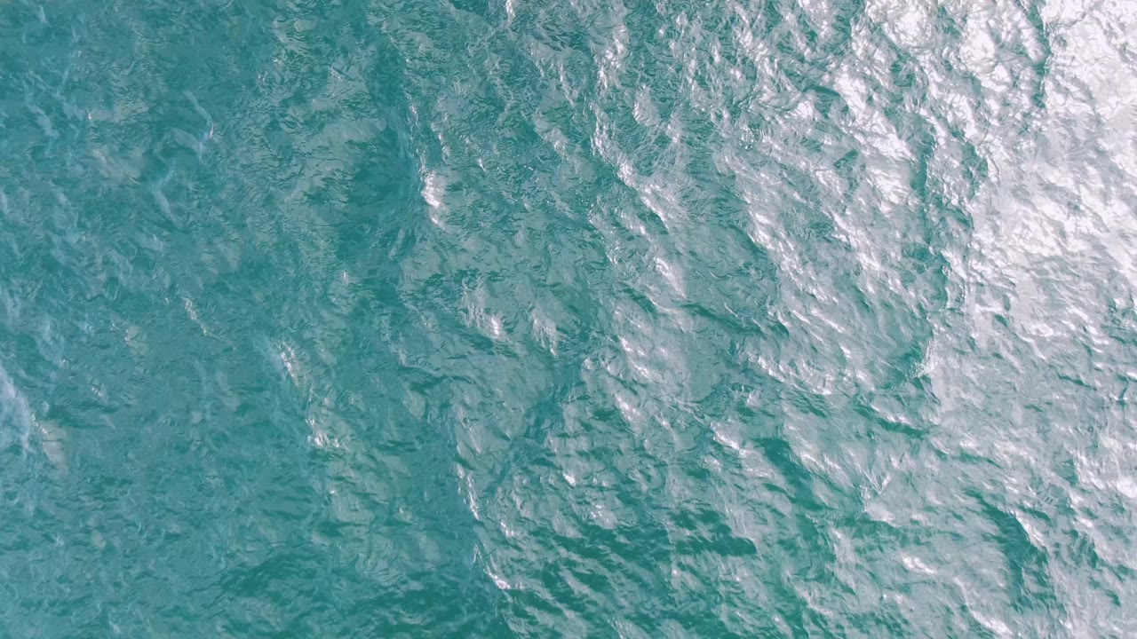 Aerial turquoise water with diagonal foam patches
