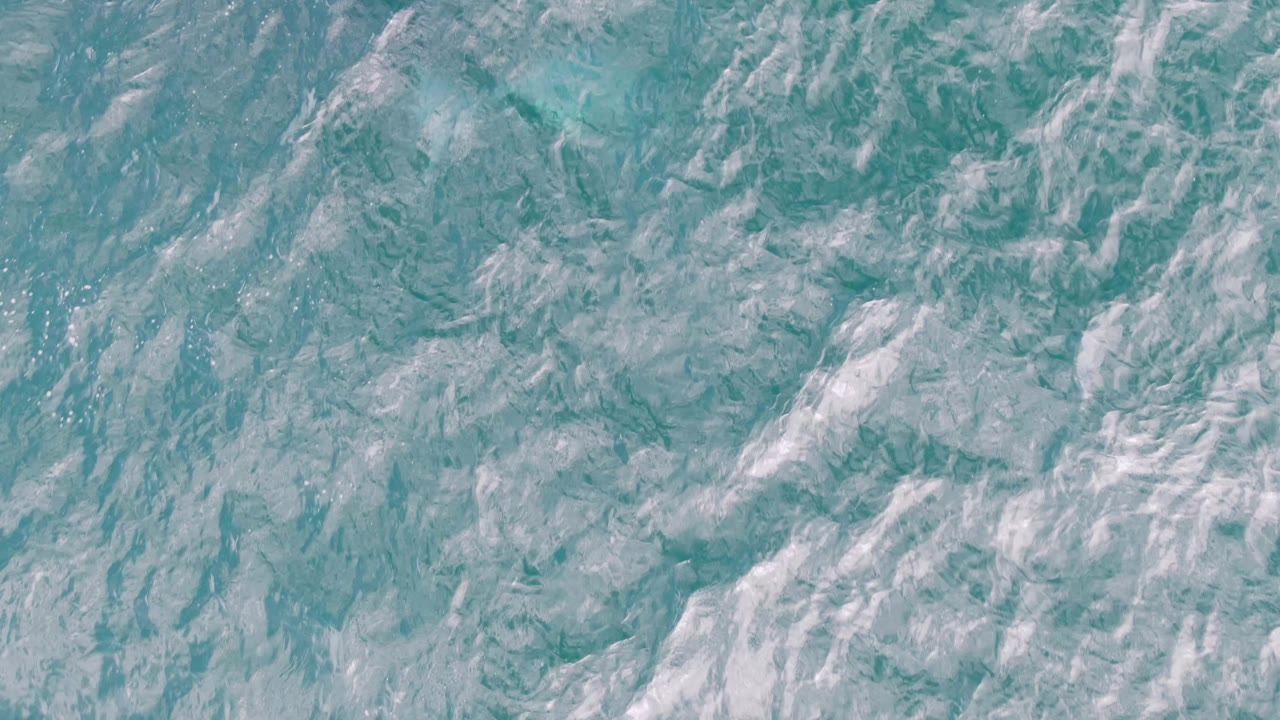 Turquoise ocean surface with white foam streaks
