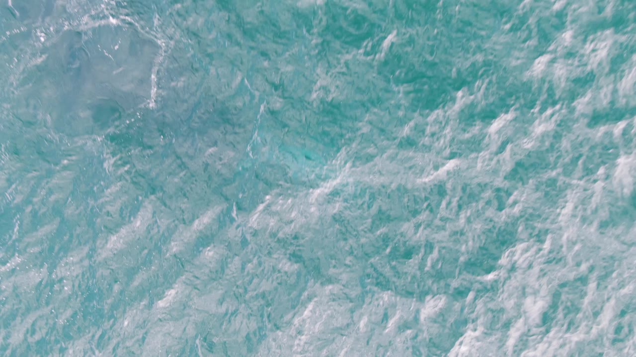 Blue-green ocean water at Shipwrecks, Baja California Sur, with dense ripples, white foam patches, and no visible people.