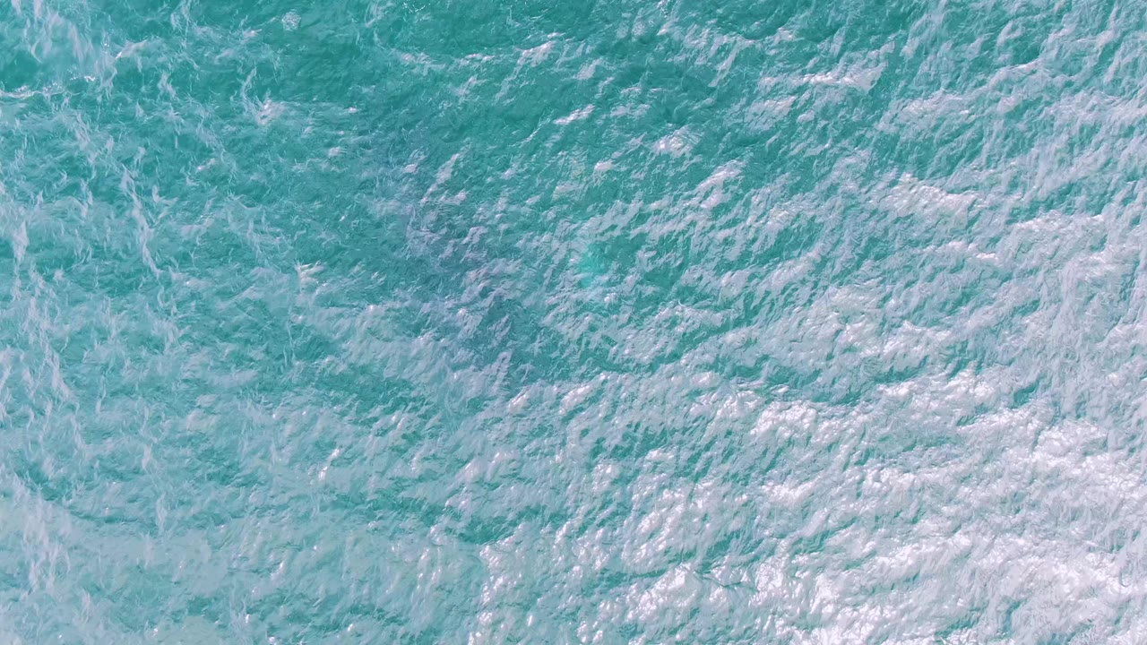 Turquoise water at Shipwrecks, Baja California Sur, Mexico fills the frame as pale foam gathers in softer bands, with no visible people.