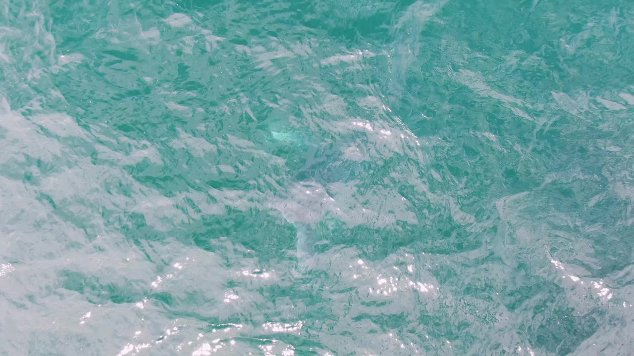 Turquoise ocean surface with white foam streaks