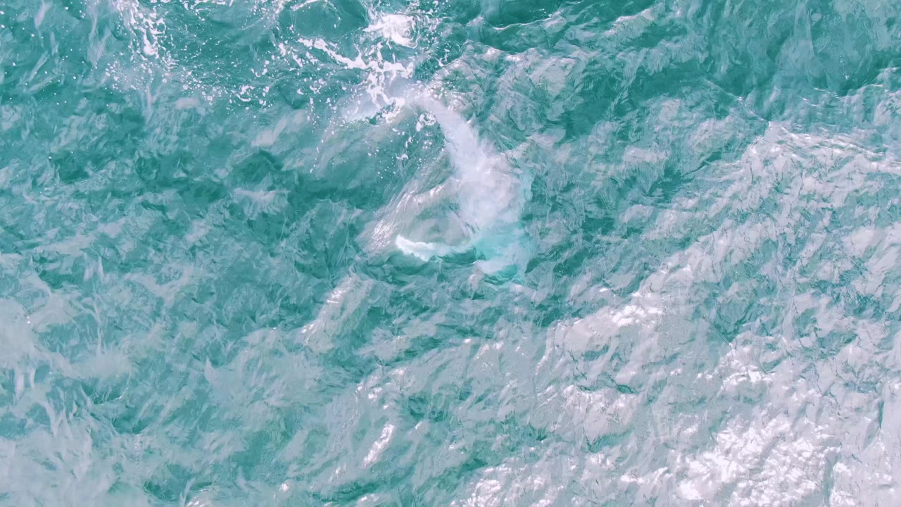 Turquoise sea surface at Shipwrecks, Baja California Sur, with layered ripples and pale foam traces, and no visible people in frame.