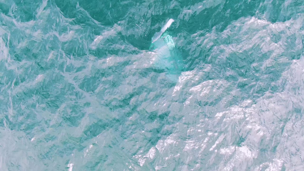 Top-down view of turquoise ocean water at Shipwrecks, Baja California Sur, with white foam streaks and no visible people.