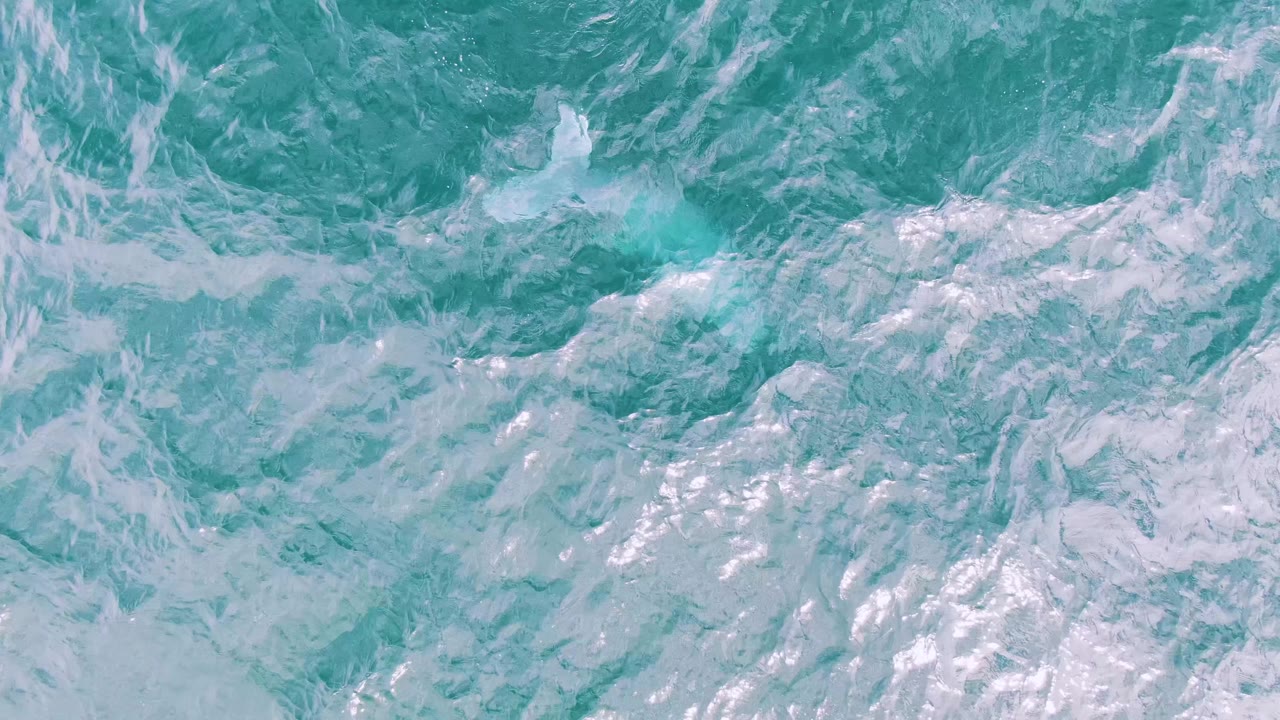 Turquoise ocean water fills the frame at Shipwrecks, Baja California Sur, with pale foam patterns, scattered highlights, and no visible people.
