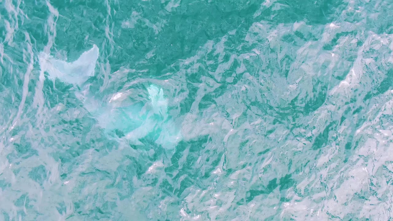 Turquoise ocean surface with white foam patterns