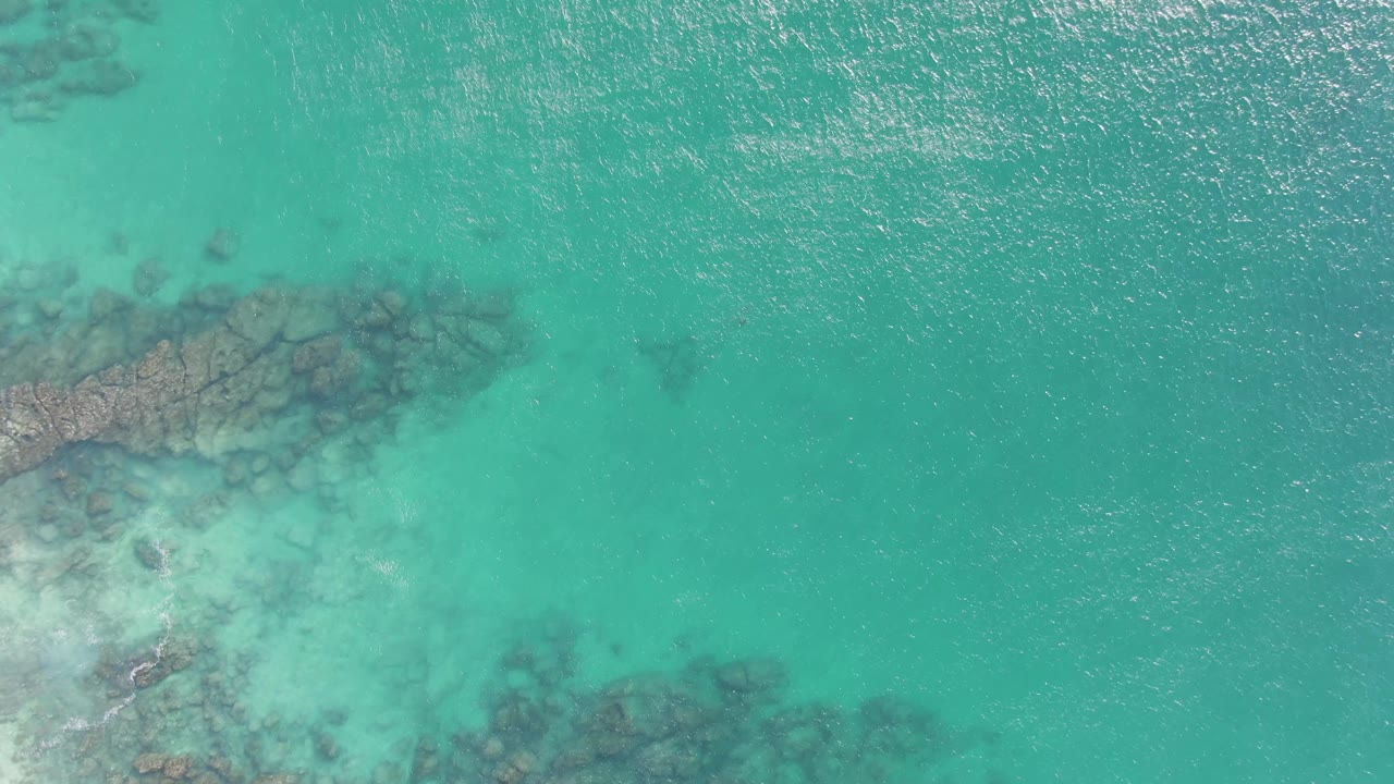 Fourth frame from Buzzards Beach in Baja California Sur with rocky underwater formations concentrated on the left, pale shallow water below them, and no visible people.