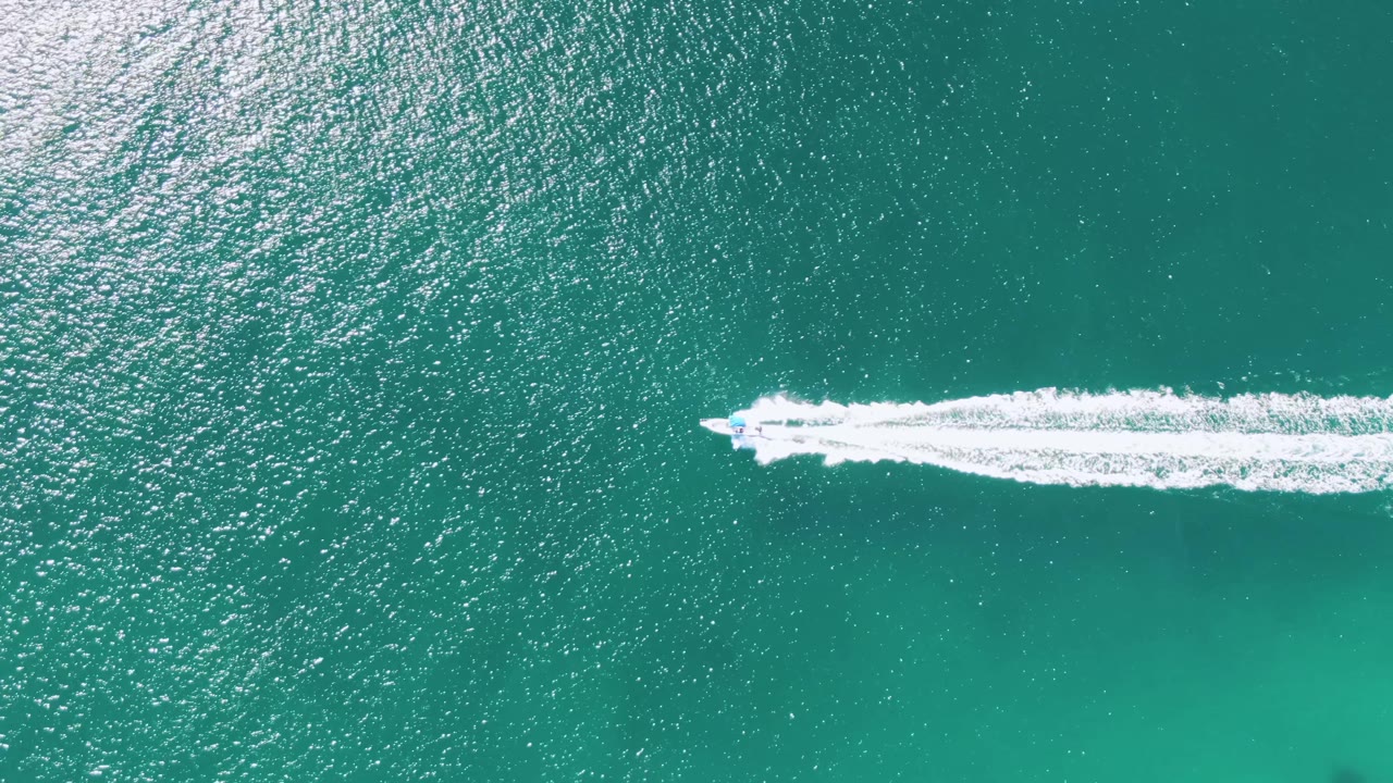 Speedboat and wake across clear turquoise water
