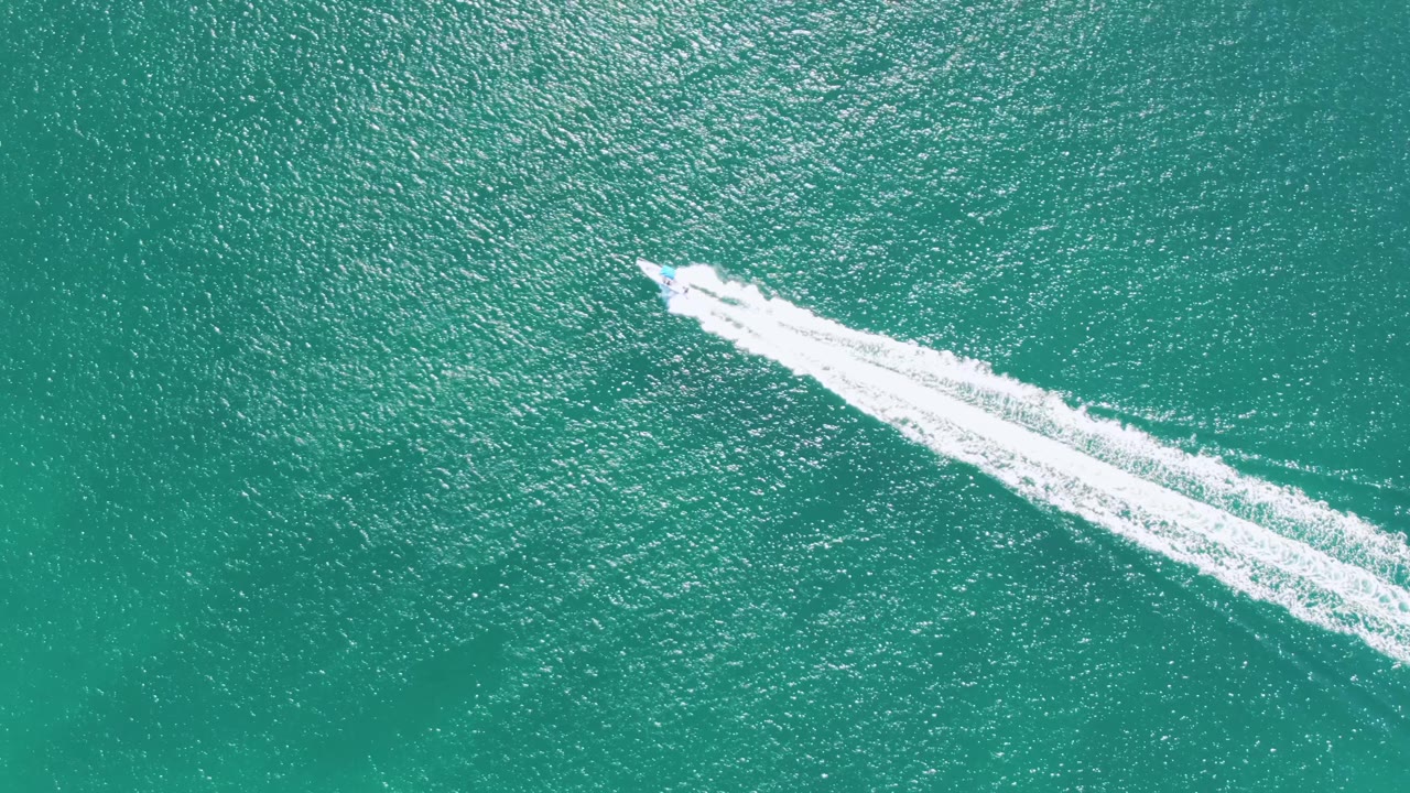 Speedboat leaving a white wake across turquoise water.