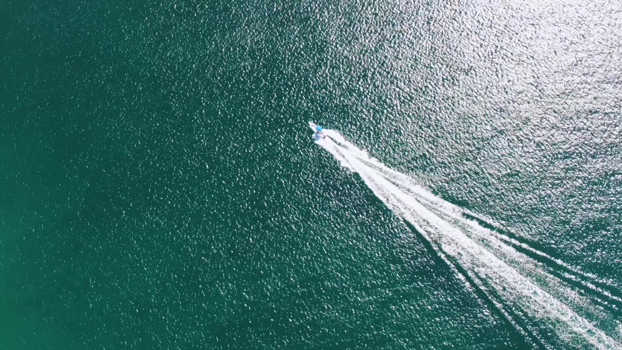 Speedboat crossing green-blue ocean with white wake