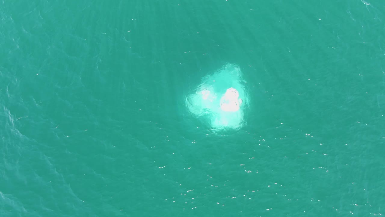 At Buzzards Beach in Baja California Sur, a small bright white foamy disturbance sits in open turquoise water with no visible people.