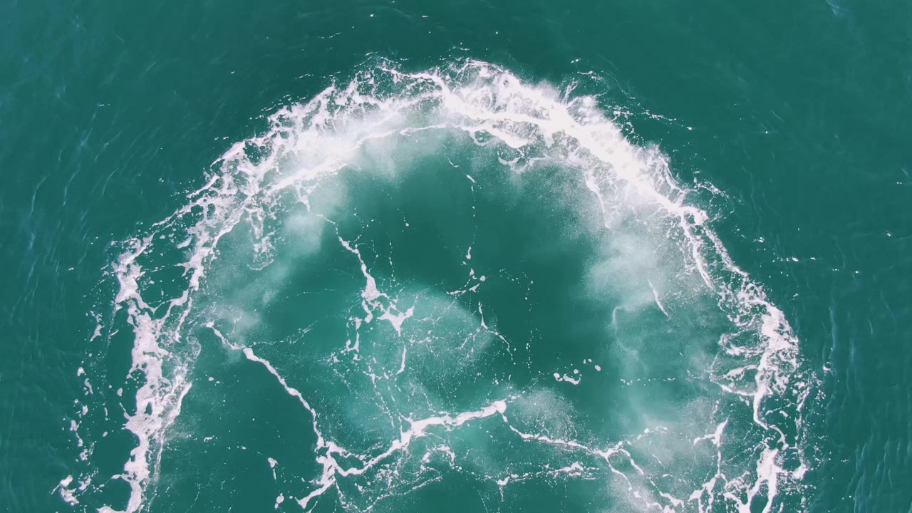 White circular boat wake in turquoise ocean water.