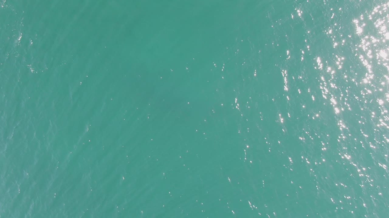 Turquoise ocean surface with scattered sunlight glints.