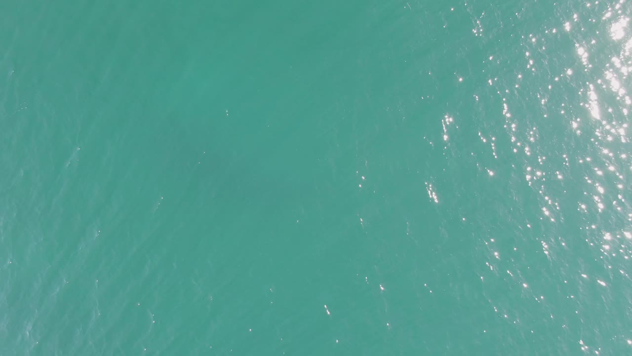 Open turquoise sea surface in Baja California Sur with most sunlight glints concentrated along the right side and no visible people.