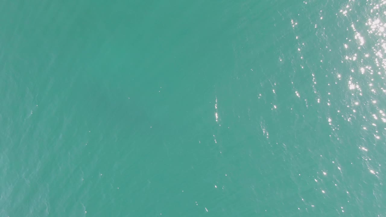 Turquoise ocean surface at Buzzards Beach with narrow white reflections running through the upper middle and no visible people.