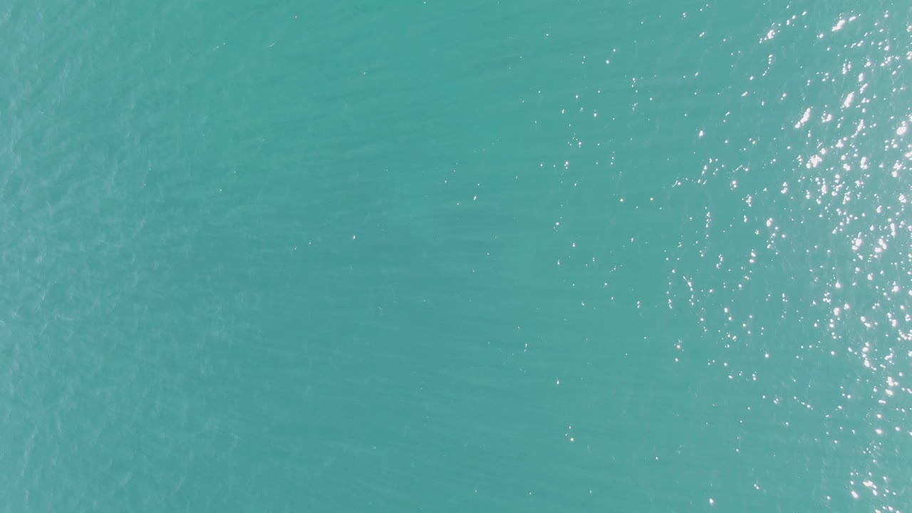 Clear turquoise water with soft ripples and shifting bright highlights.