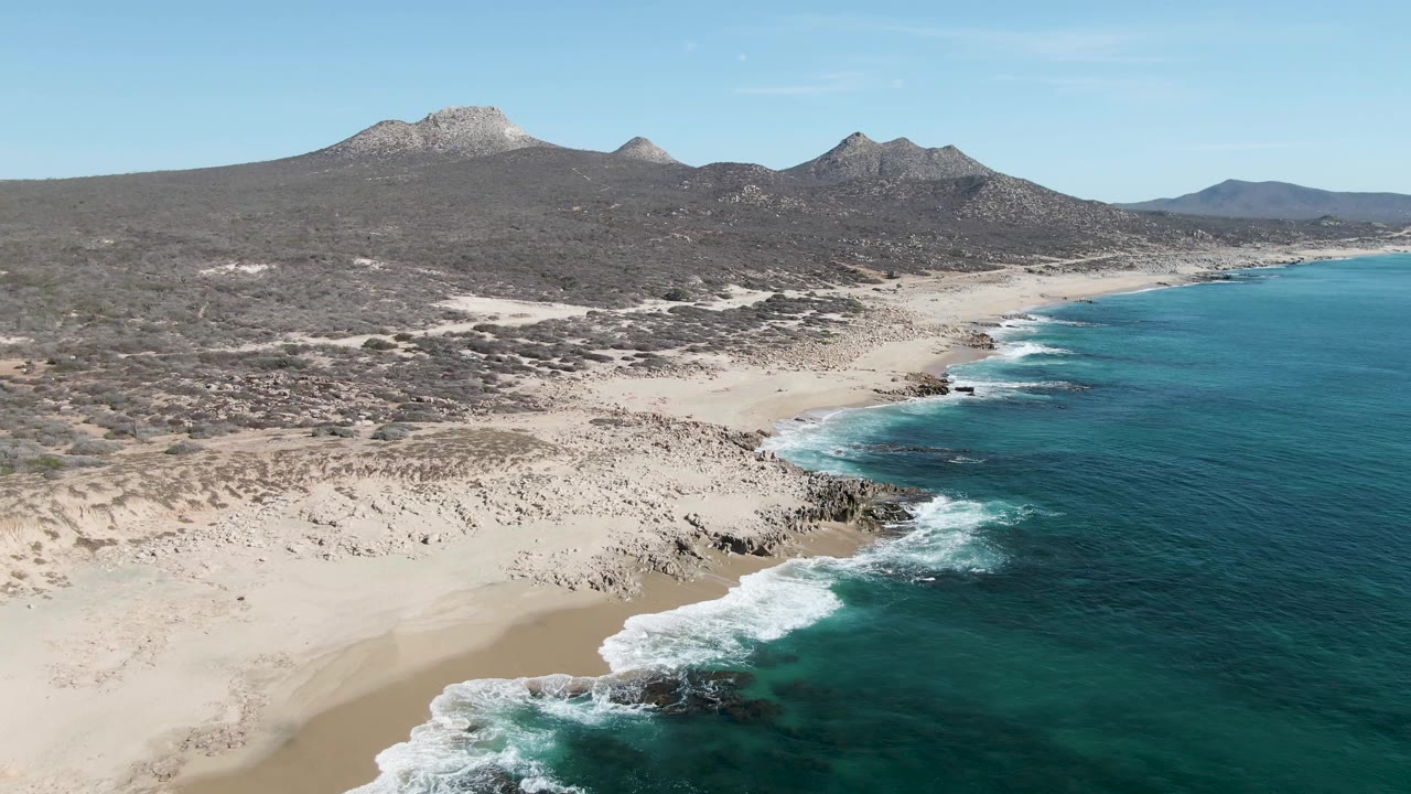 Aerial view of sandy coast, turquoise ocean, and mountains