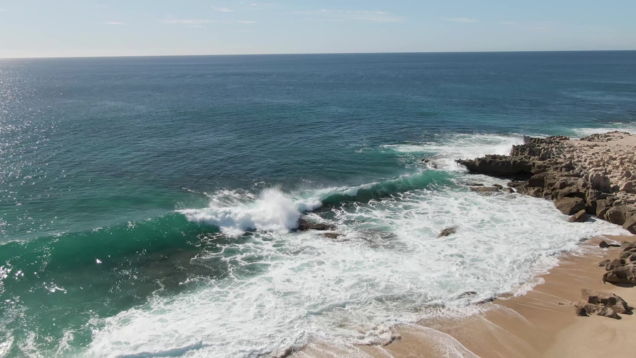 Wave breaking near rocks on a sandy beach