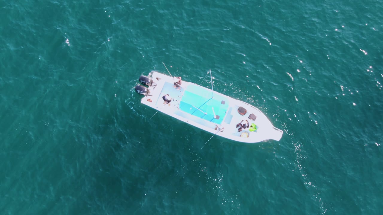 White boat with passengers floating over blue-green water.