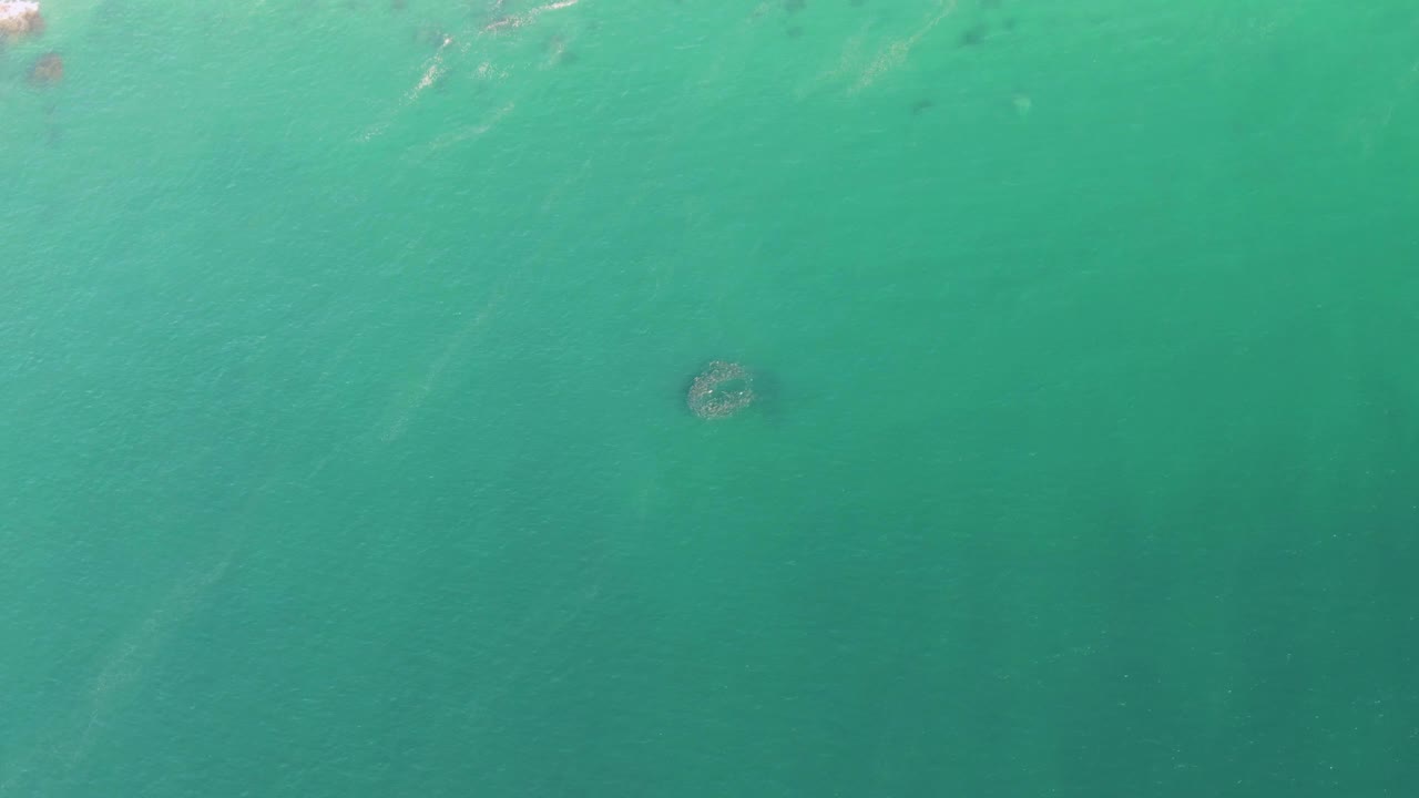 Turquoise ocean water with a dark circular underwater formation