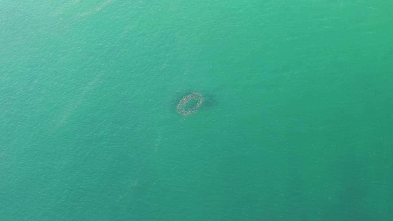 Aerial view at Buzzards Beach with a small circular structure left of center in clear turquoise water, with no visible people or vessels.